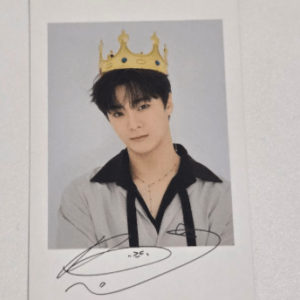 Polaroid portrait of a young man wearing a gold crown, light gray jacket with black collar, posing for a studio photo with a signature on the bottom edge