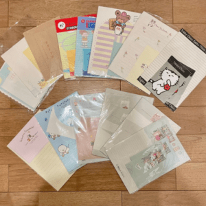 Assorted cute character-themed notebooks and notepads laid out on a wooden floor.