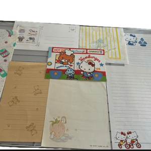 Assortment of decorative letter papers with Hello Kitty and pastel patterns laid out on a metal display tray.