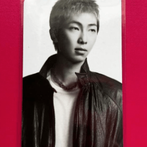 Black-and-white portrait of a young person with short light hair wearing a leather jacket against a pink background.