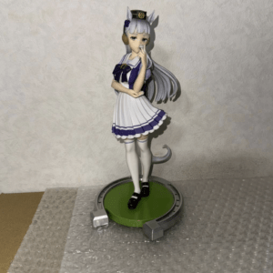 Figure of a cat-eared anime girl in a white and purple sailor uniform standing on a green circular base, posed on bubble wrap.