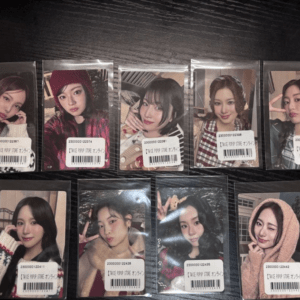Ten plastic-wrapped photo cards featuring young women in different outfits, each with a barcode sticker on the front laid out on a dark surface.