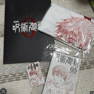 Collection of Jujutsu Kaisen merchandise on a beige rug: a black textured folder with the logo, a white-wrapped item with a red illustration, and a small manga card and larger volume displaying anime-style characters and Japanese text.