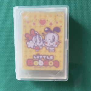 Plastic case holding a yellow cartoon card with two cute animals and a heart above them; text reads 'Little ...' in pink/red letters.