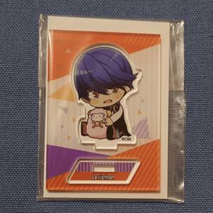 Chibi character with purple hair holding a pink teddy bear on a colorful orange and purple card in plastic packaging.