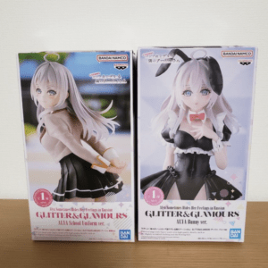 Two boxed Glitter & Glamours figures of Alya: one in a beige school uniform, the other in a black bunny maid outfit, on a wooden surface.