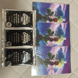Three illustrated art cards show Mario and Yoshi in a colorful space scene, arranged vertically with three black packs of card sleeves on the left.