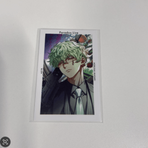 Illustrated card featuring a green-haired anime character in a suit with a gun, Paradox Live graphic at top.