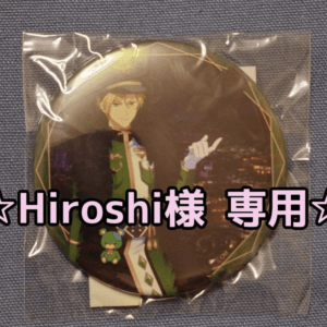 Round anime badge in plastic wrap on blue fabric; features a blond character in a green outfit with pink overlay text saying 'Hiroshi様 専用'.