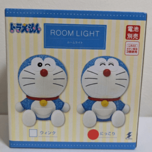 Box for Doraemon Room Light featuring two blue-and-white Doraemon figures with red noses on a yellow-striped background; product name 'ROOM LIGHT' visible on the front.