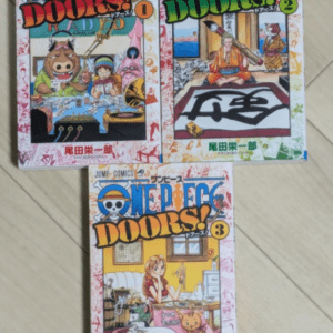Three One Piece DOORS! manga volumes 1–3 laid on a wooden floor, each with colorful cover art showing anime-style characters in playful scenes.