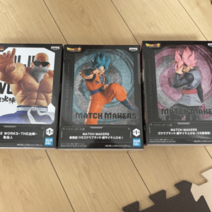 Three Dragon Ball Match Makers collectible figure boxes lined up on a wooden floor.