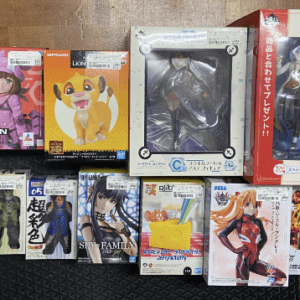 Boxed anime figures and figurines of various characters lined up on a wooden shelf.