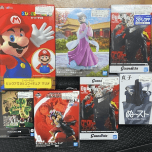 Assorted boxed figure sets on a black surface, featuring Mario from Nintendo, a princess in a purple kimono, and anime figures from Grandista and other lines.