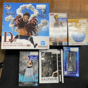 Large box featuring Monkey D. Luffy from One Piece Masterlise EXPECÉ, surrounded by other boxed figures ready for display on a wooden floor.