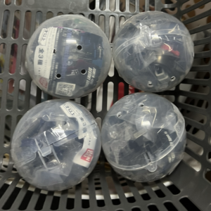Four round clear plastic containers with labels and small holes, placed in a gray shopping basket.