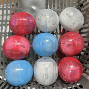 Nine plastic capsule toys in a gray basket, arranged in a 3x3 grid in pink, blue, and white.