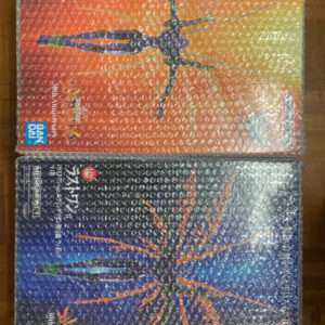Two Bandai model kits in bubble wrap boxes, each depicting a multi-legged arachnid robot with orange and purple coloring on the top box and orange and teal on the bottom, against gradient backgrounds.