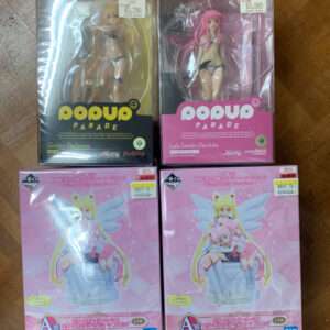 Boxed anime figures on a wooden floor: Pop Up Parade Golden Darkness and Lala Satalin Deviluke, with two pink Eternal Sailor Guardian statues below in pink boxes.