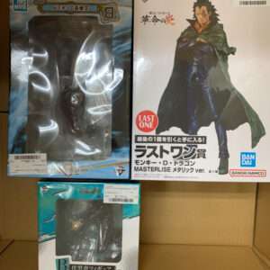 Three boxed anime figures on a shelf: a large blue-packaged figure on the left, a Masterlise Monkey D. Dragon box on the right, and a smaller turquoise-box figure at the bottom.