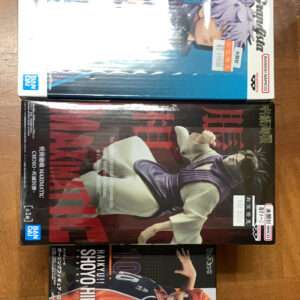 Three Bandai anime figure boxes stacked on a wooden floor, with a blue-haired character on the top box.