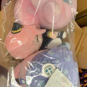 Plastic-wrapped pink plush stuffed animals inside a bag, resting on a purple star-pattern blanket.