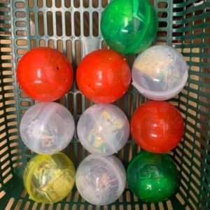 Few colorful plastic balls arranged in a green basket: red, yellow, green, and translucent white balls in a grid pattern.