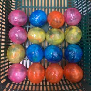 Fifteen translucent plastic balls in pink, blue, orange, and yellow arranged in a green shopping basket.