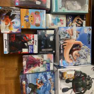 Assorted anime figure boxes laid on a wooden floor, featuring characters from Naruto, One Piece, Dragon Ball, and more.