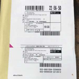 Two stacked Japanese receipt sheets with barcodes and printed text on a yellow padded envelope; shows dates like 2026/05/21 and various tracking numbers/boxes.