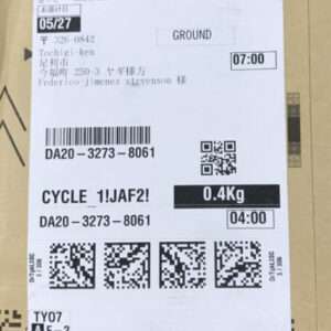 Package shipping label on a cardboard box showing destination, tracking barcodes, a weight of 0.4 kg, and QR codes; includes times like 07:00 and 04:00 and alphanumeric codes.