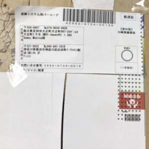 Box with a large white shipping label containing barcodes and Japanese text, plus a red caution sticker on the side.