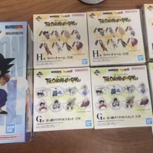 Boxed Dragon Ball Z figures on a wooden table: a large Goku Masterline box on the left and multiple smaller 'The Chronicles of Goku' figure boxes on the right with character stickers.