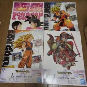 Four Dragon Ball poster prints laid on a wooden floor, featuring Goku in various forms and related characters from The Chronicle of Goku collection.