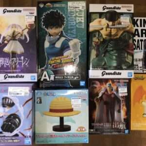A collection of boxed anime figures on a wooden floor, mostly Grandista boxes with characters in dynamic poses (female warrior, blue-clad hero, muscular swordsman) and a bright orange box featuring a cute character on the right.