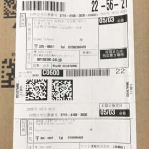 Shipping label on a cardboard box with barcodes, QR codes, and Japanese text (Amazon.co.jp).