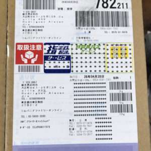 Cardboard package with multiple barcodes, Japanese text, and warning icons on the shipping label.