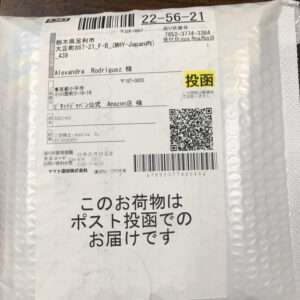 White padded shipping envelope with a Japanese label, barcodes, a QR code, and a yellow 投函 stamp; text on the label notes delivery by mail drop.