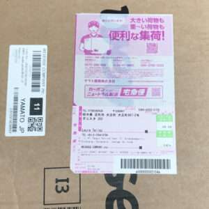 Cardboard package with a pink Japanese shipping label affixed to the top and a white barcode label on the side; large black 13 printed on the box.