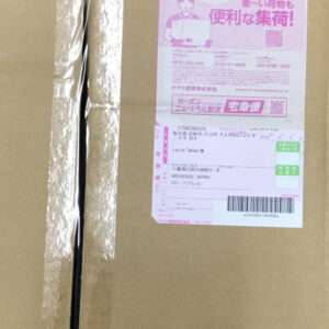 Brown cardboard parcel with a pink shipping label showing Japanese text and a barcode, affixed to the front.