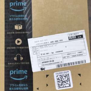 Brown Amazon package with a shipping label, barcode, and a QR code on the front surface.