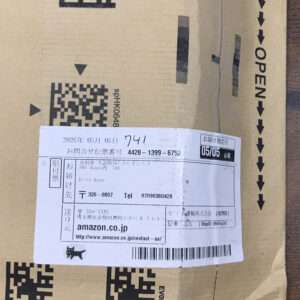 Box with a white shipping label containing Japanese text, barcode, and a tracking number, attached to a brown cardboard package.