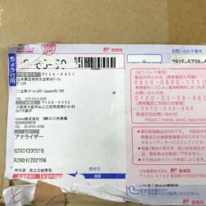 Japanese parcel with shipping label showing a barcode, recipient/sender details on a cardboard box