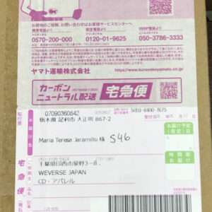 Box with pink promotional panel on top and a white shipment label below; recipient Maria Teresa Jaramillo, address in Japan, and a barcode are visible.  Articulos Japan (Post Box Japan)