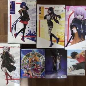 Boxed anime figures arranged on a wooden floor, featuring colorful character boxes with stylized poses and outfits.