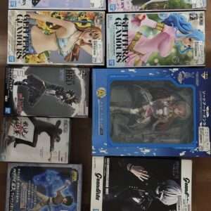 A grid of boxed anime figures from various series stacked on a wooden floor, showing colorful character art on box fronts.
