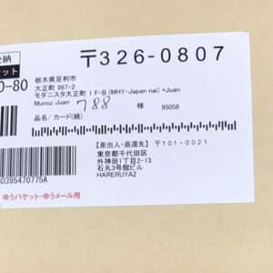 Japanese parcel/郵便物 label attached to a brown envelope, showing barcodes, tracking number, and recipient address details (ゆうパケット).