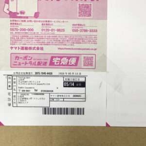 Japanese parcel label with pink branding, barcode, and QR code on white background