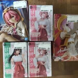 Several anime figure boxes arranged on a wooden surface, featuring colorful character art and Japanese text (Hololive on left, other figures in the center and right).