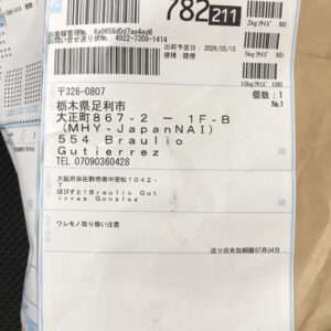 Brown padded package with a blue Japanese shipping label showing barcodes, tracking numbers, and sender/recipient information (recipient named Gutierrez).